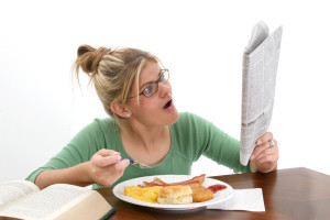 young woman reading newspaper at breakfast